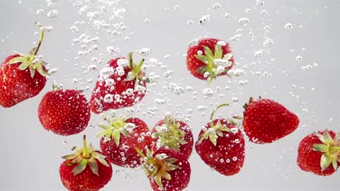 A bunch of strawberries falling through water