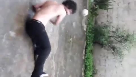 Shirtless man black pants kicks ball falls back