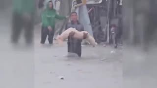 Palestinian boy carrying the lifeless body of a child