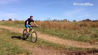 Kid falls off yellow bike after making a jump