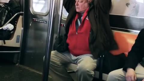 Old man on subway raises his arms up and moves them slowly