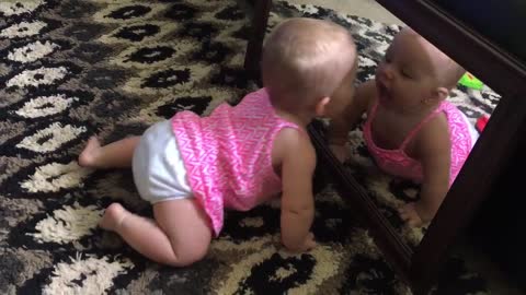 Baby repeatedly kisses her mirror reflection