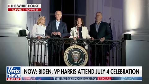 Biden grabs Kamala's hand and holds it up as they watch the fireworks