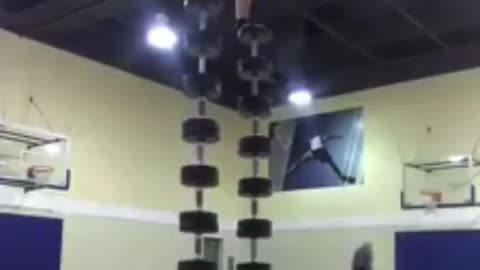Guy balances on and does a pushup on dumbbell tower