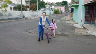 Camila ensinando a Júlia andar de bicicleta