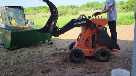 Mini Skidsteer Grappling out Manure in Stalls