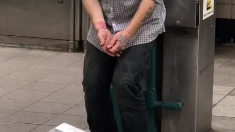 Man in blue hat falling asleep standing up in subway station