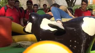 Two girls fall slow motion off mechanical bull