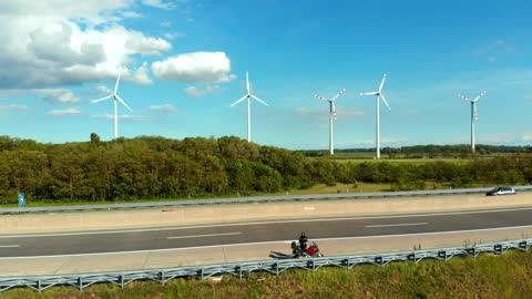 Motorcycle on the highway with a wind farm behind