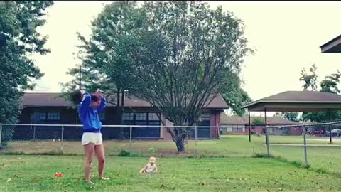 Baby laughs at dog playing with a stick