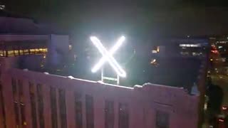 View of newly installed illuminated 𝕏 logo atop corporate HQ, captured in stunning detail by drone