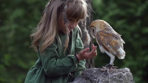 Little girl with an owl in a fairy forest. Friends