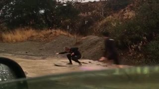 Guys trying to paddle and surf down muddy wet flooded street