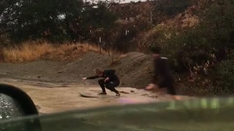 Guys trying to paddle and surf down muddy wet flooded street