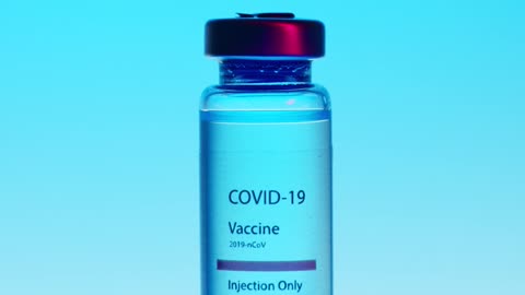 A Close-Up View of a Covid-19 Vaccine Vial on Blue Background