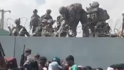 US soldiers pull a baby over a wall outside of the Kabul airport.