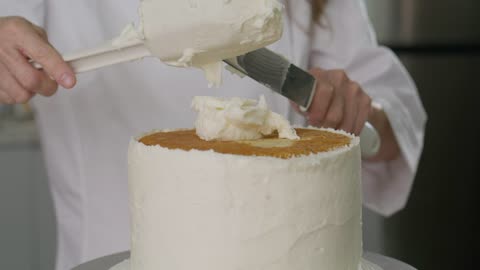 Pastry chef covering a cake with white icing