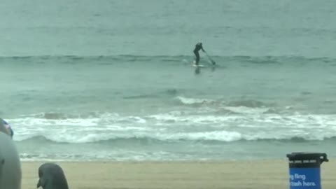 Man rides surfboard far out in ocean