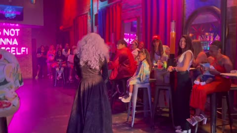 WARNING GRAPHIC: Neon Sign at Drag Show for Kids Reads, "It's Not Gonna Lick Itself"