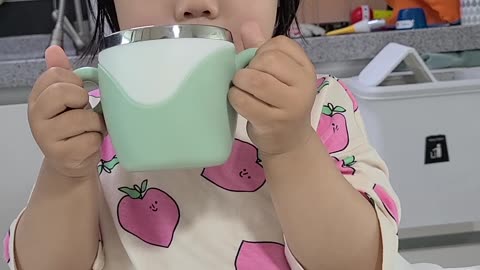 A child uses both hands to drink milk