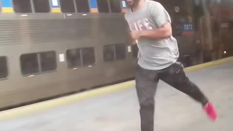 Guy red hat life shirt running next to moving train station platform