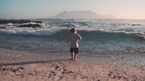 A small child is surprised by a wave