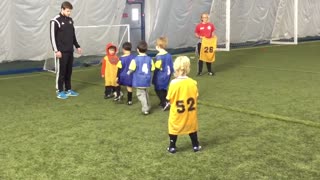 Little boy in yellow trips a boy in a blue shirt soccer game