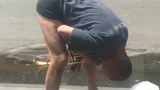 Guy playing trumpet with head between legs