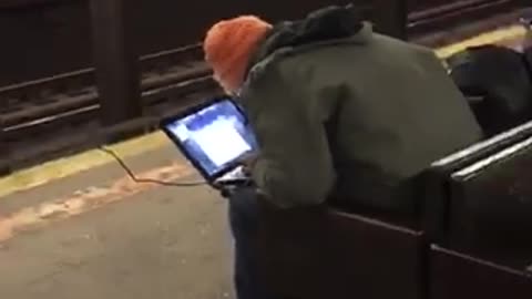 Guy orange hat charging laptop roof of station