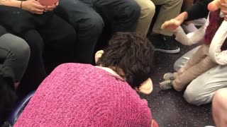 Two people on subway acting out as dolls on subway floor screaming