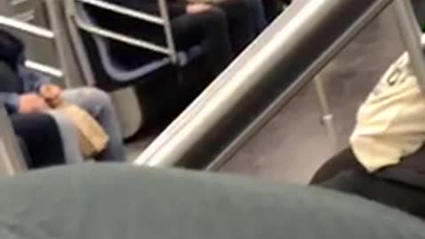 Man has a chucky doll sitting on his lap on subway train
