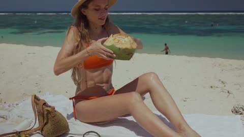 A Woman Drinking Fresh Coconut Juice at the Beach