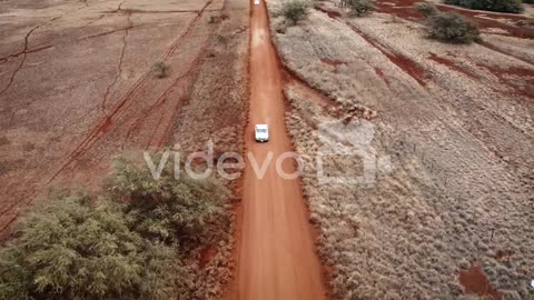Aerial over two white cars chasing or following each other on a dirt road in Molokai Hawaii from Mau
