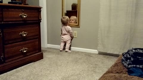Baby girl fascinated by her reflection