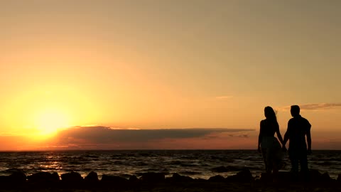 Silhouettes of a couple holding hands at sunset