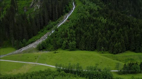 aerial footage apline valley with river pine tree forest and waterfall tirol austria