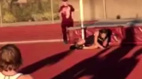 Track runner jumps backwards over bar and misses, fall off safety pad onto ground