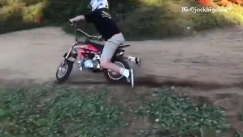 Boy in red dirt bike over hill falls off