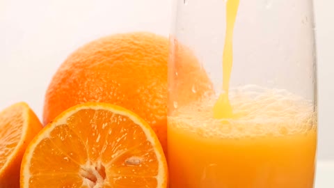 Serving juice in a glass with some oranges on a white background