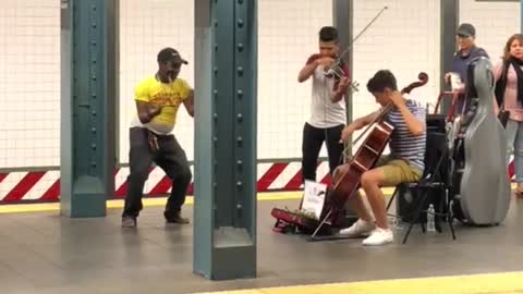 Guy yellow shirt dancing to violin duo subway