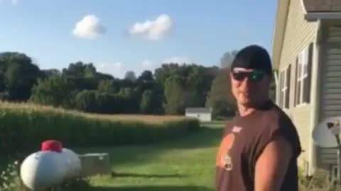 Man in black cut off shirt jumps into corn field