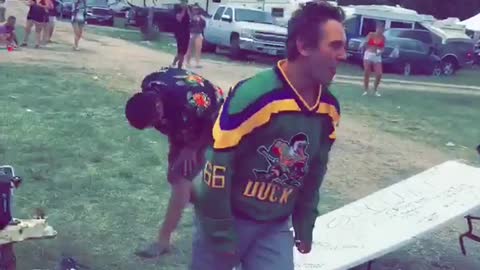 Man in green jersey does a flip gainer off of an rv onto a table