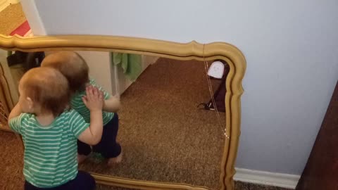 Baby adorably hugs and kisses his own reflection