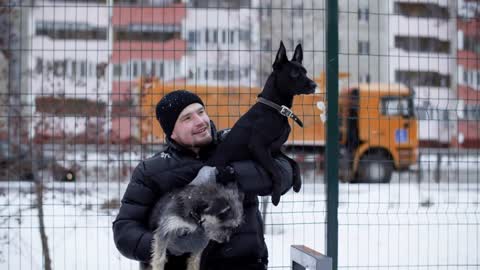 Happy man hugging two dogs on outdoor walk in winter city