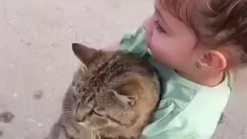baby girl huging a cat