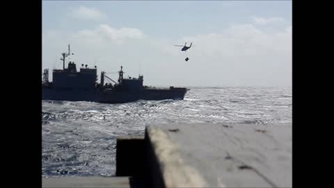 Navy helicopter in extreme high seas lifting supply's off ship