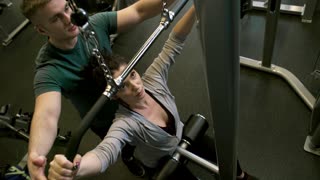 A Man Assisting A Woman In Using The Flat Pulldown Weights Equipment In A Gym