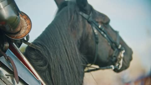 A man knight in armor riding a horse - a foot in the stirrups