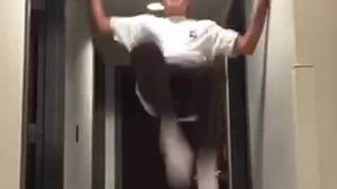 Kid in white shirt in hallway attempts backflip and fails