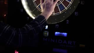 Hand put on remove dartboard barely missed by red dart